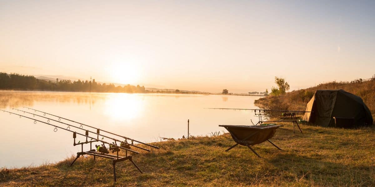 Carp rods on a pod beside a lake at sunrise