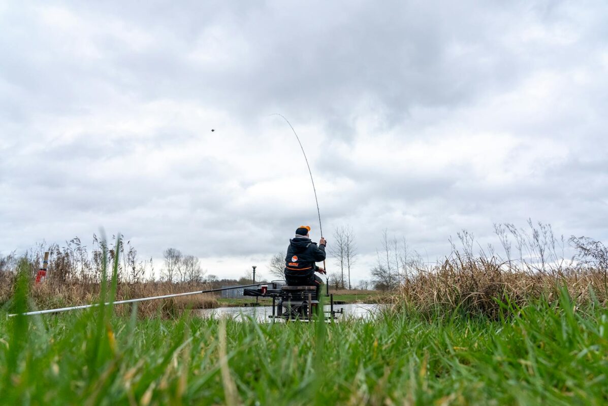 Angler on a fishing platform with the Guru Aventus R feeder rod fully loaded playing a fish across open water