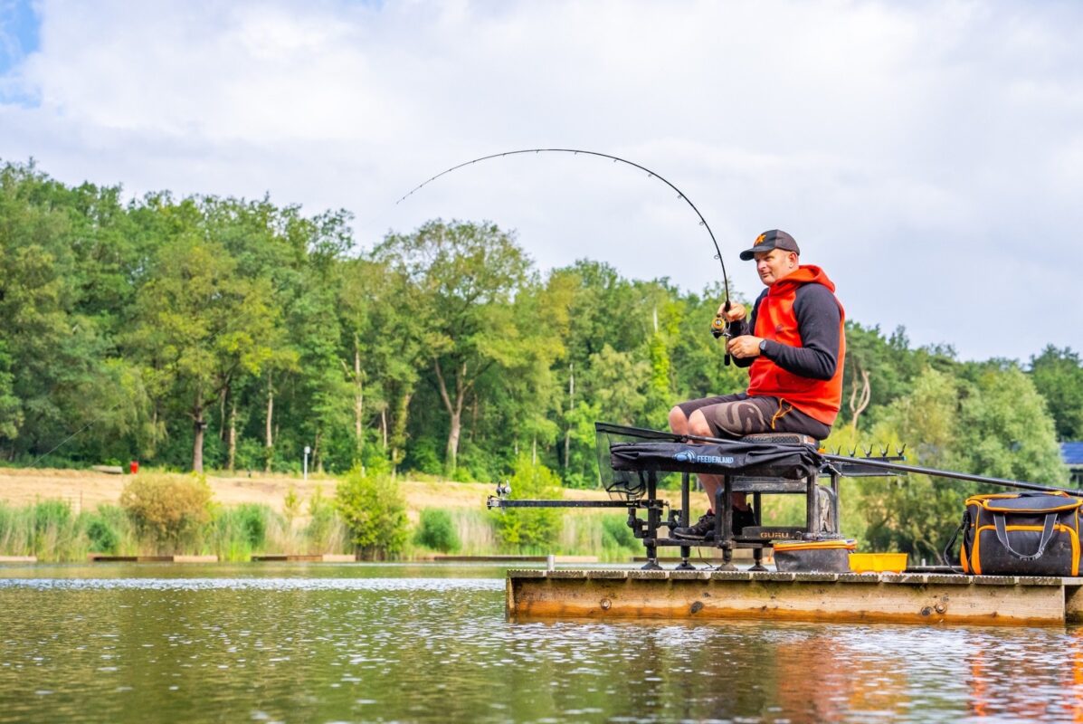 An angler playing a fish on a feeder rod bent through the blank